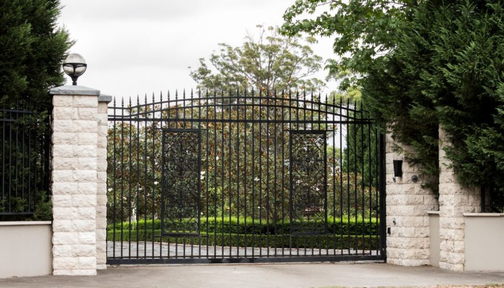 Black wrought iron metal driveway entrance gates set in brick fence